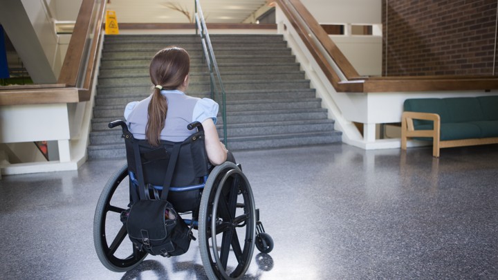 Woman with Spina Bifida in wheelchair studying difficulty of accessing stairway