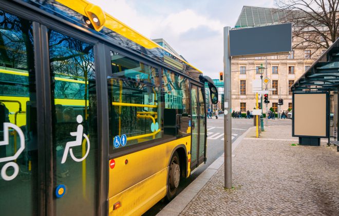 Yellow public bus with entrance door for people with disability at the bus stop in Berlin Mitte in City centre. Street in Germany in Europe. (Yellow public bus with entrance door for people with disability at the bus stop in Berlin Mitte in City centre